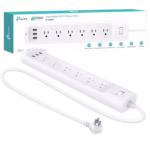 Kasa Smart Power Strip with six controlled outlets and three USB ports charging multiple devices on a desk.